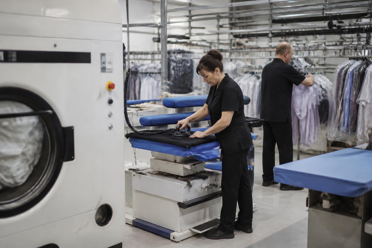 Dry cleaning machine, pressing tables and garment conveyor in the processing area of a UK dry cleaning works