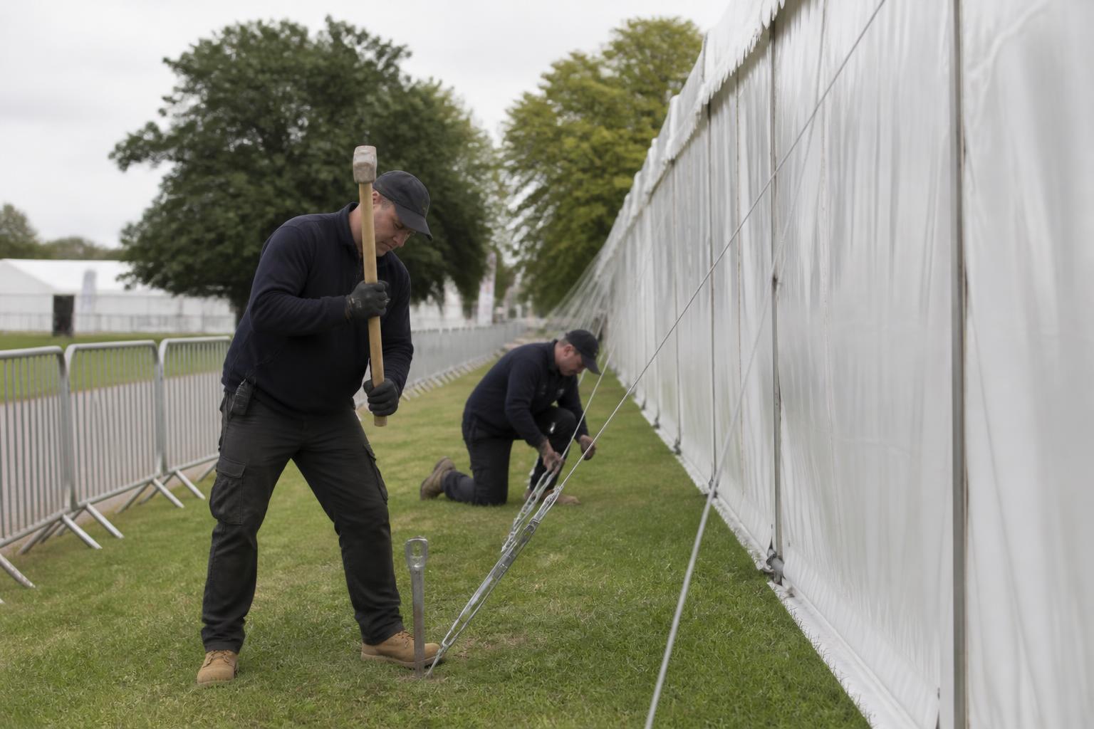 Marquee Hire Insurance 2 Two crew members driving ground stakes and tensioning guy lines beside a clearspan structure at a UK county show
